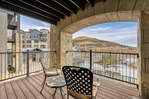 A balcony with a stone arch, two chairs, and a view of a hilly landscape. - Heart Of Canyons Village Walk To Lifts 226 1 Bedroom Condo (Park City)