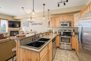 A modern kitchen with granite countertops, stainless steel appliances, wooden cabinets, and a built-in island with a sink. - Heart Of Canyons Village Walk To Lifts 226 1 Bedroom Condo (Park City)