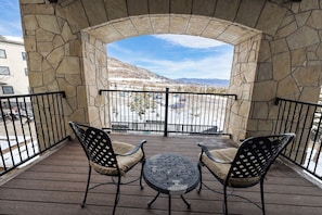A covered outdoor seating area with stone walls and a view of a snowy landscape. - Heart Of Canyons Village Walk To Lifts 226 1 Bedroom Condo (Park City)