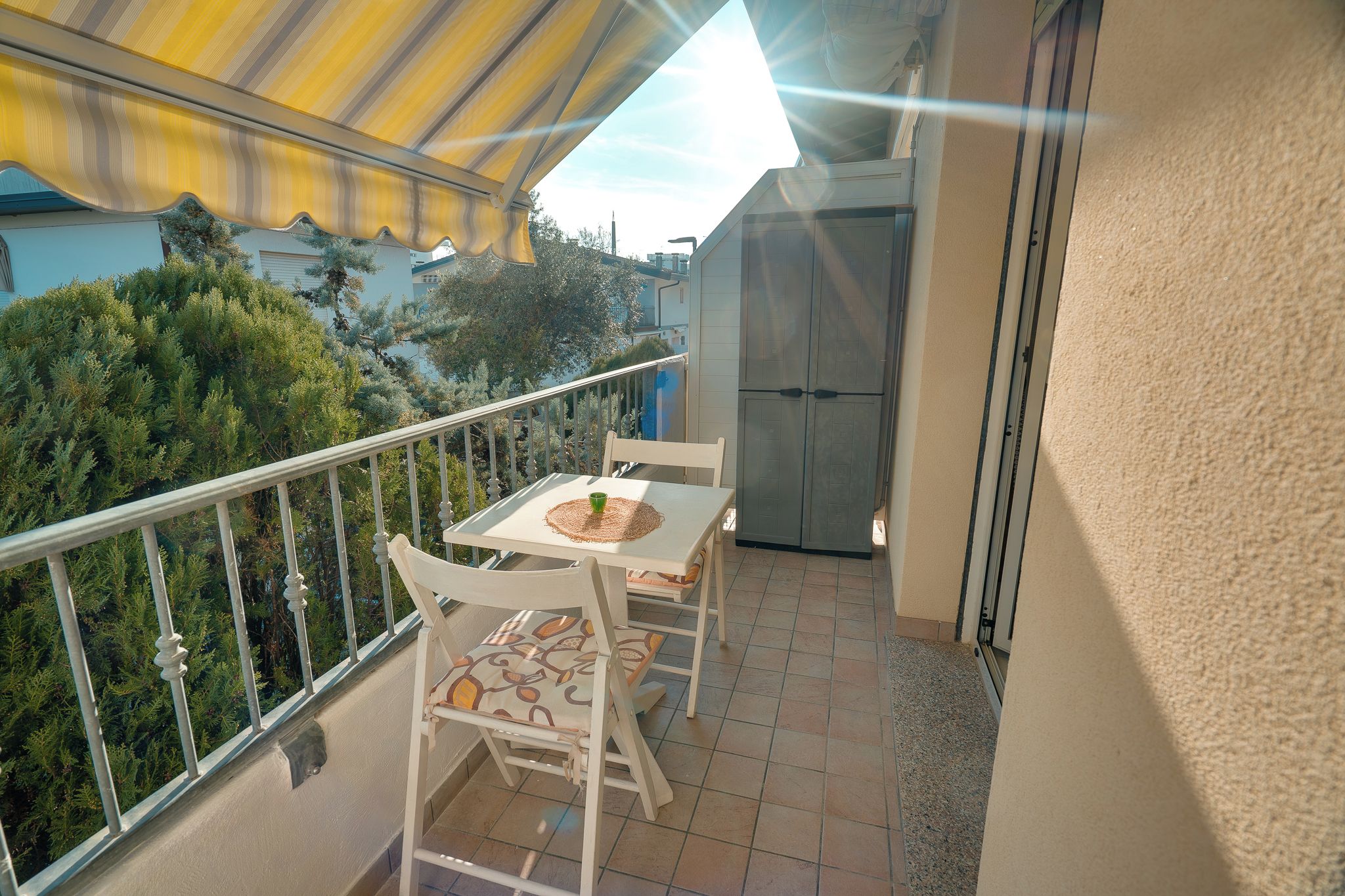 A balcony with a table and chairs, a door, and a railing.