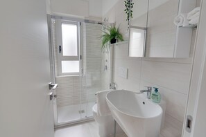 A modern bathroom with a glass shower enclosure, a white sink, and a mirror above the sink. - Family Garden - a 350 Dalla Spiaggia con Terrazza (Lignano Sabbiadoro)