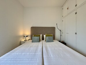 Ein Schlafzimmer mit zwei Betten, einem Nachttisch, einer Lampe und einem Kleiderschrank.