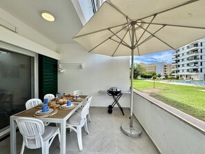 A balcony with a table set for breakfast, outdoor seating, and a view of the pool and buildings. - Vilamoura Downtown 3 With Pool by Homing (Loulé)