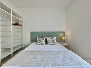 A bedroom with a bed, a headboard, a nightstand with a lamp, and a wardrobe. - Vilamoura Downtown 3 With Pool by Homing (Loulé)
