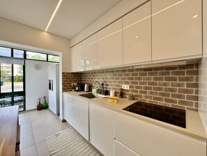 A modern kitchen with white cabinets, a brick backsplash, and a built-in stove. - Vilamoura Downtown 3 With Pool by Homing (Loulé)