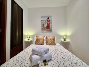 A hotel room with a bed, two bedside lamps, a painting on the wall, and a set of towels on the bed. - Albufeira Typical 2 by Homing (Albufeira)