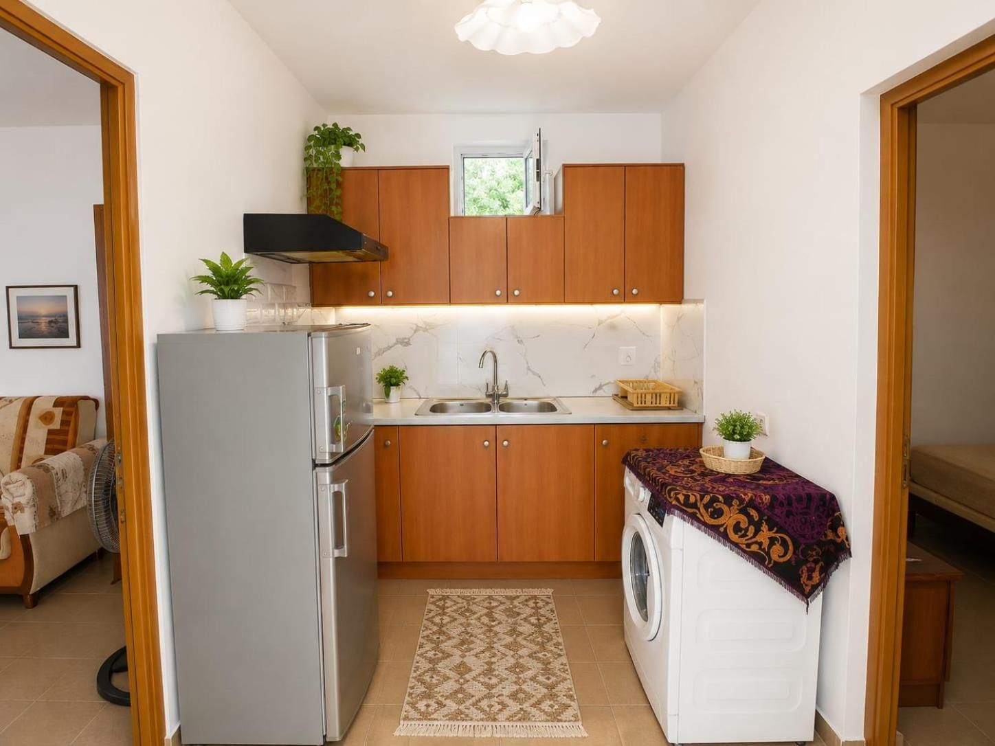 Une cuisine compacte avec des meubles en bois, un four encastré, un évier et un lave-linge.