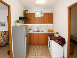 Une cuisine compacte avec des meubles en bois, un four encastré, un évier et un lave-linge.
