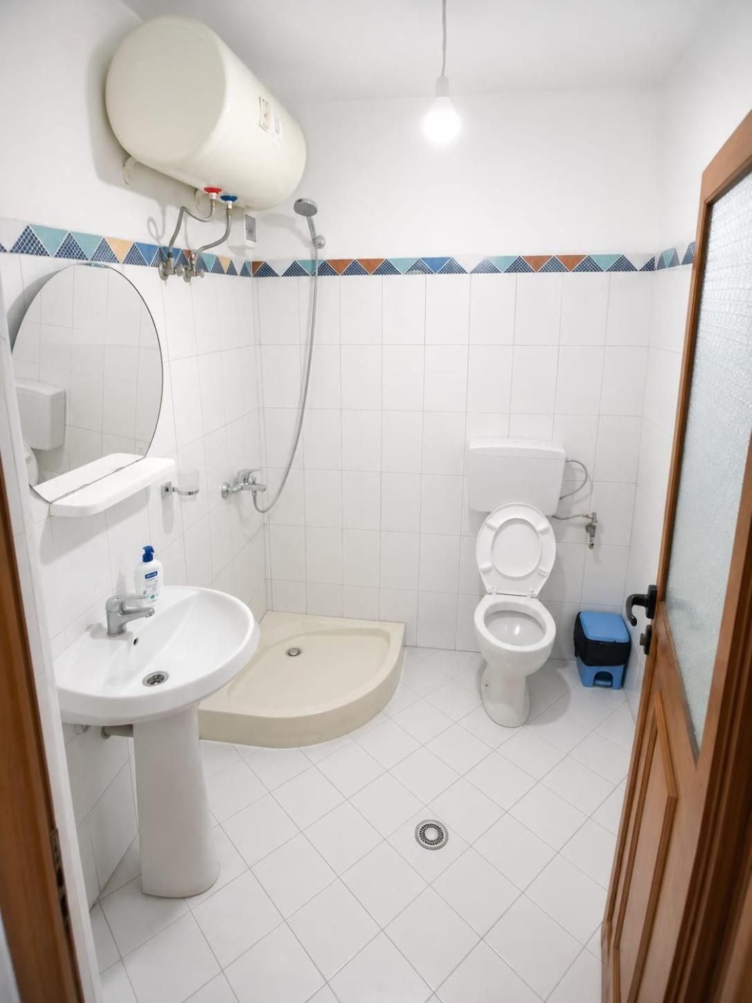 A bathroom with a sink, mirror, toilet, shower, and a towel rack.