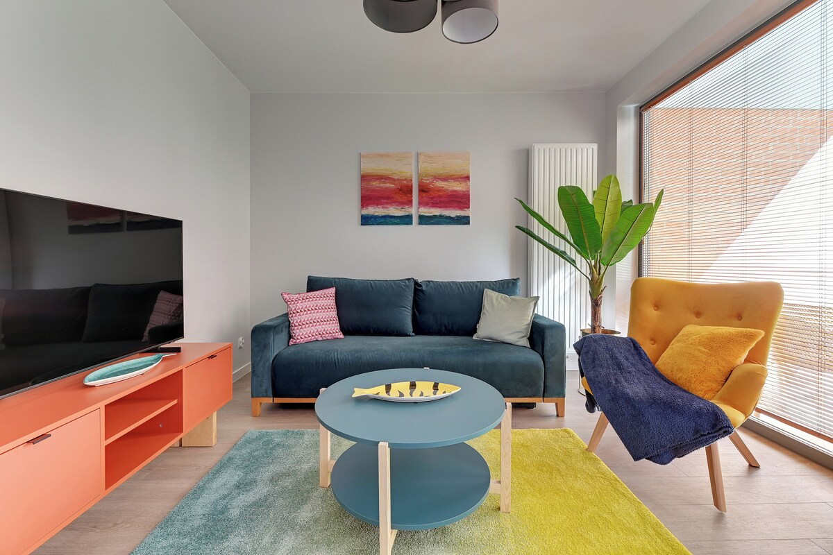 Ein modernes Wohnzimmer mit einer Couch, einem Fernseher, einem Couchtisch und einer Pflanze.