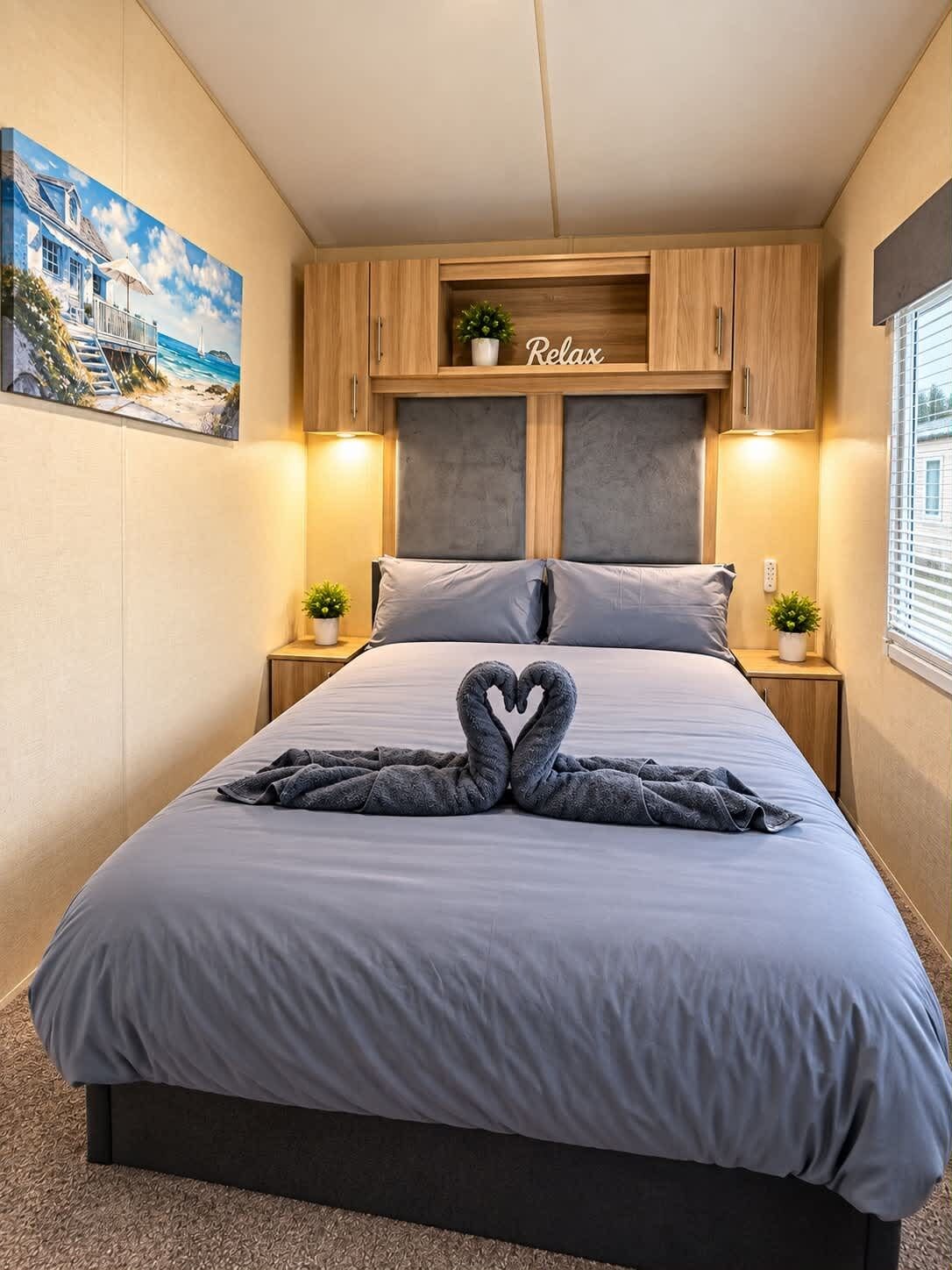 Un dormitorio con cama, cabecera, mesitas de noche y un cuadro en la pared.