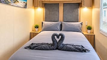 Un dormitorio con cama, cabecera, mesitas de noche y un cuadro en la pared.