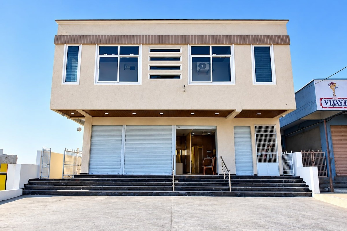 A two-story building with a flat roof, large windows, and a set of double doors at the entrance.