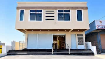 A two-story building with a flat roof, large windows, and a set of double doors at the entrance.