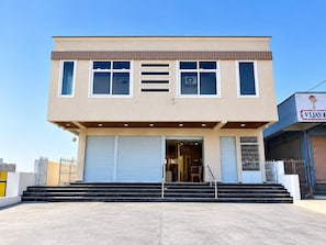 A two-story building with a flat roof, large windows, and a set of double doors at the entrance.