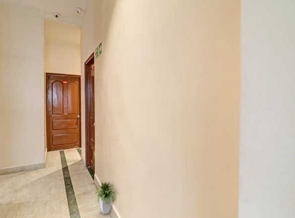 A hallway with a wooden door, a potted plant, and a tiled floor. - Hotel O Dhone Railway Junction (Dhone)