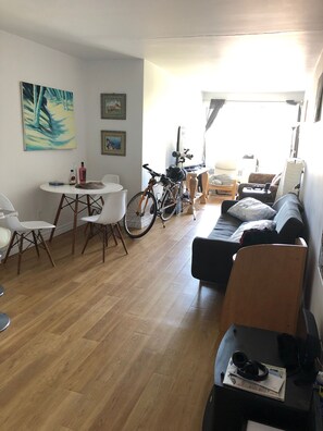 A living room with a sofa, a dining table with chairs, a bicycle, and artwork on the walls. - Furnished 1BR downtown by McGill metro, balcony with Mount Royal view (Montréal)