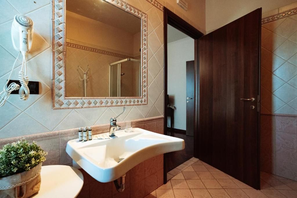 Un baño con lavamanos, espejo, secador de pelo y puerta.