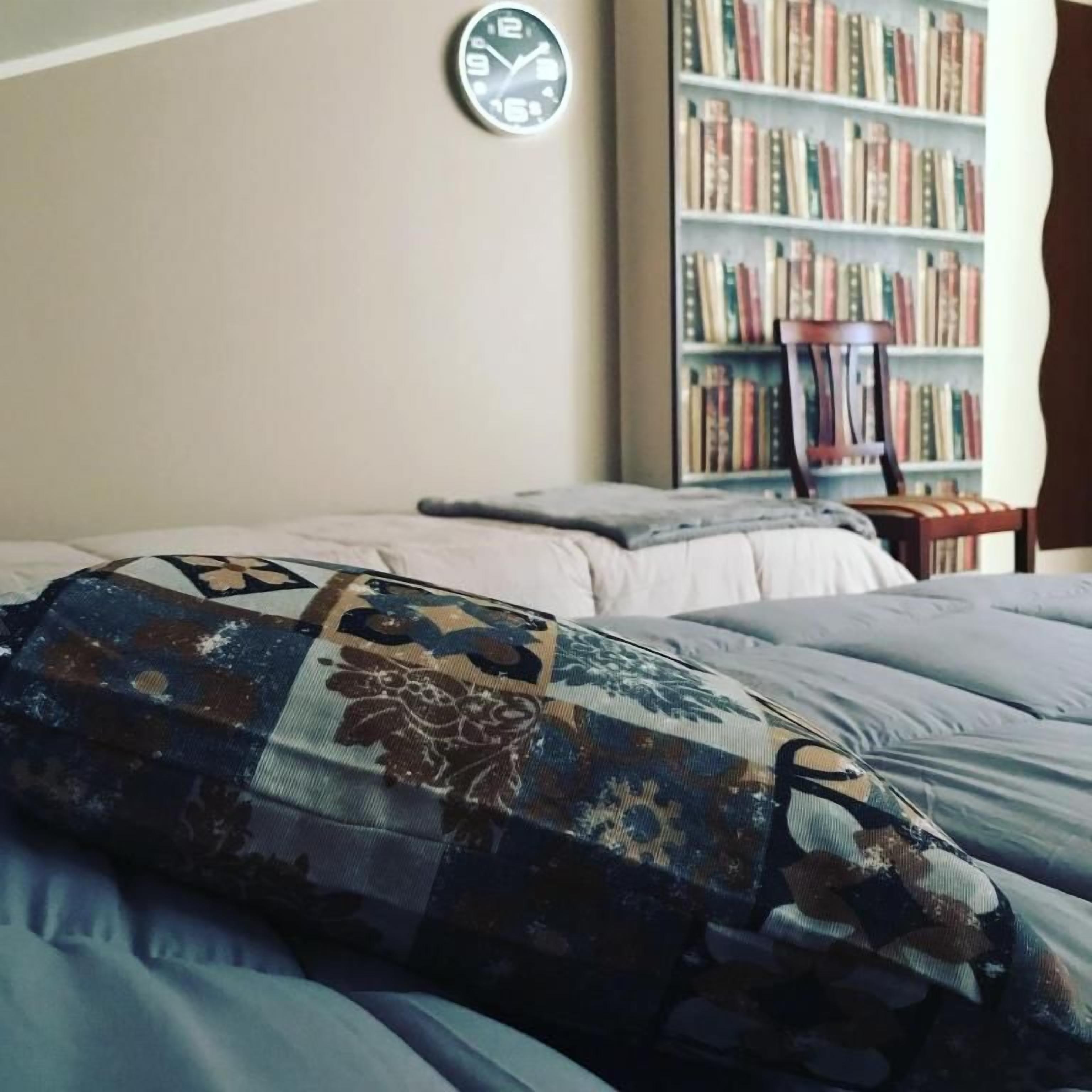 Un dormitorio con cama, estantería y reloj de pared.
