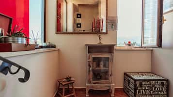 Een kamer met een spiegel, een kastje, een klein krukje en een decoratieve doos met tekst.
