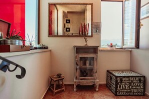 A room with a mirror, a cabinet, a small stool, and a decorative box with text.