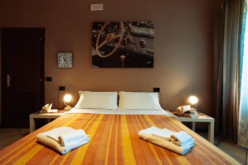 A hotel room with a large bed, two bedside tables, a clock, and a painting on the wall.