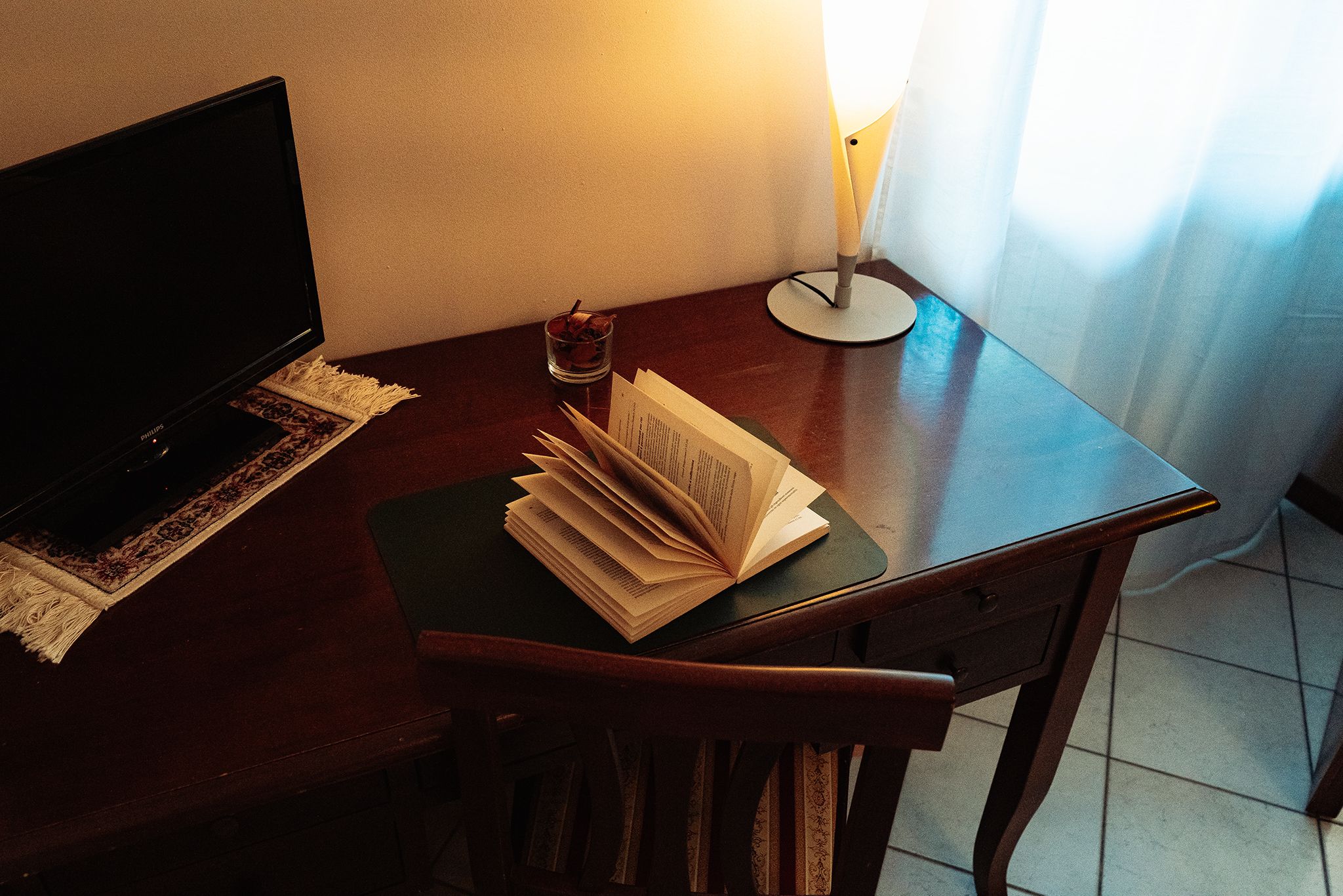 Ein Schreibtisch mit einem Laptop, einem Glas Wasser und einer Papierstapel.