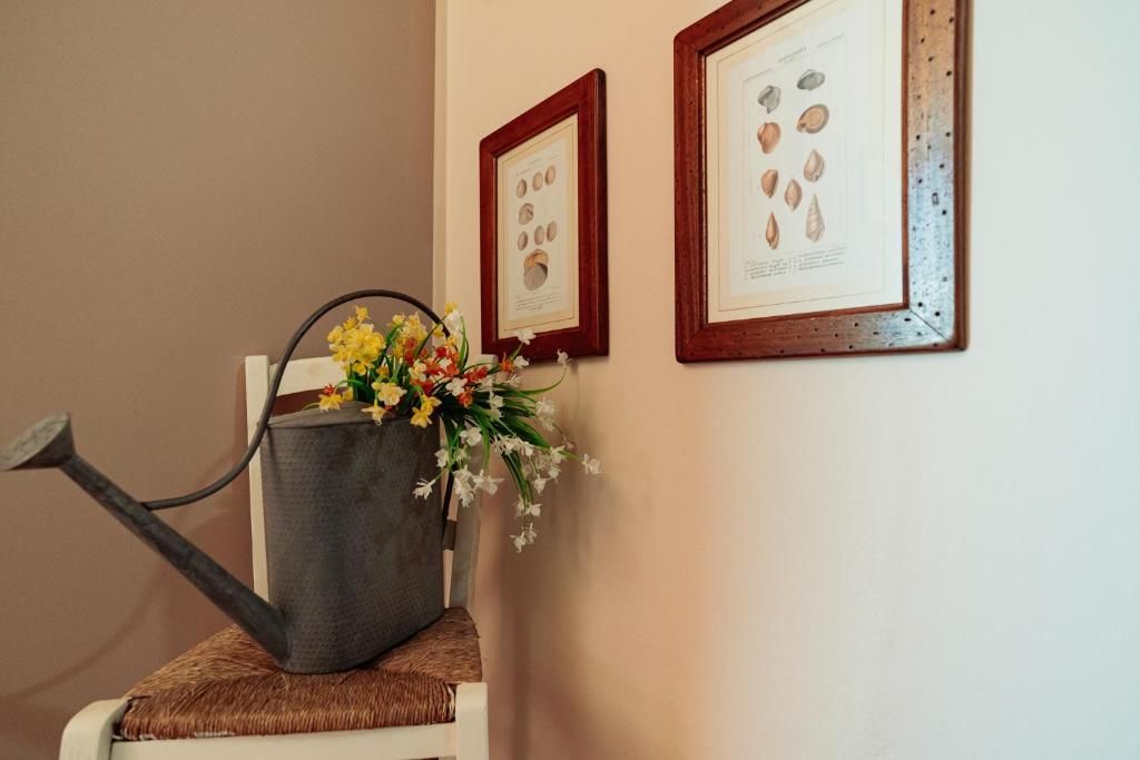 Ein Stuhl mit einer grauen Gießkanne und einem Blumenstrauß darauf.