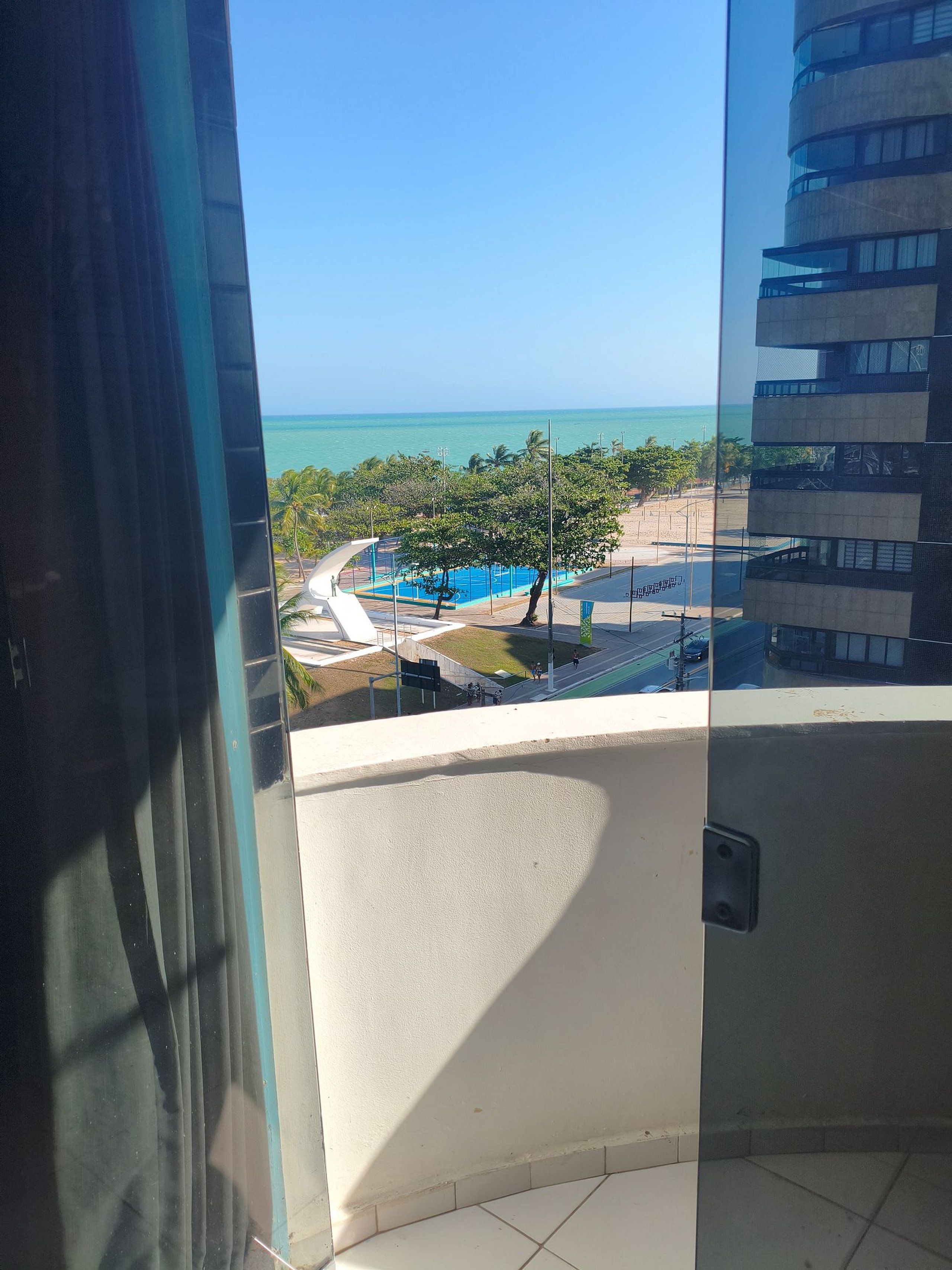 A balcony with a view of a swimming pool and a building with multiple balconies.
