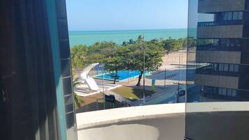 A balcony with a view of a swimming pool and a building with multiple balconies.