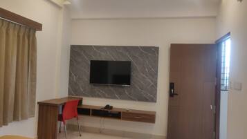 Une chambre moderne avec un téléviseur fixé au mur en marbre, un bureau avec une chaise et une armoire.