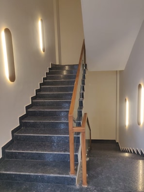 A staircase with wooden handrails and wall-mounted lighting. - SPH Comforts (Bhogadi)