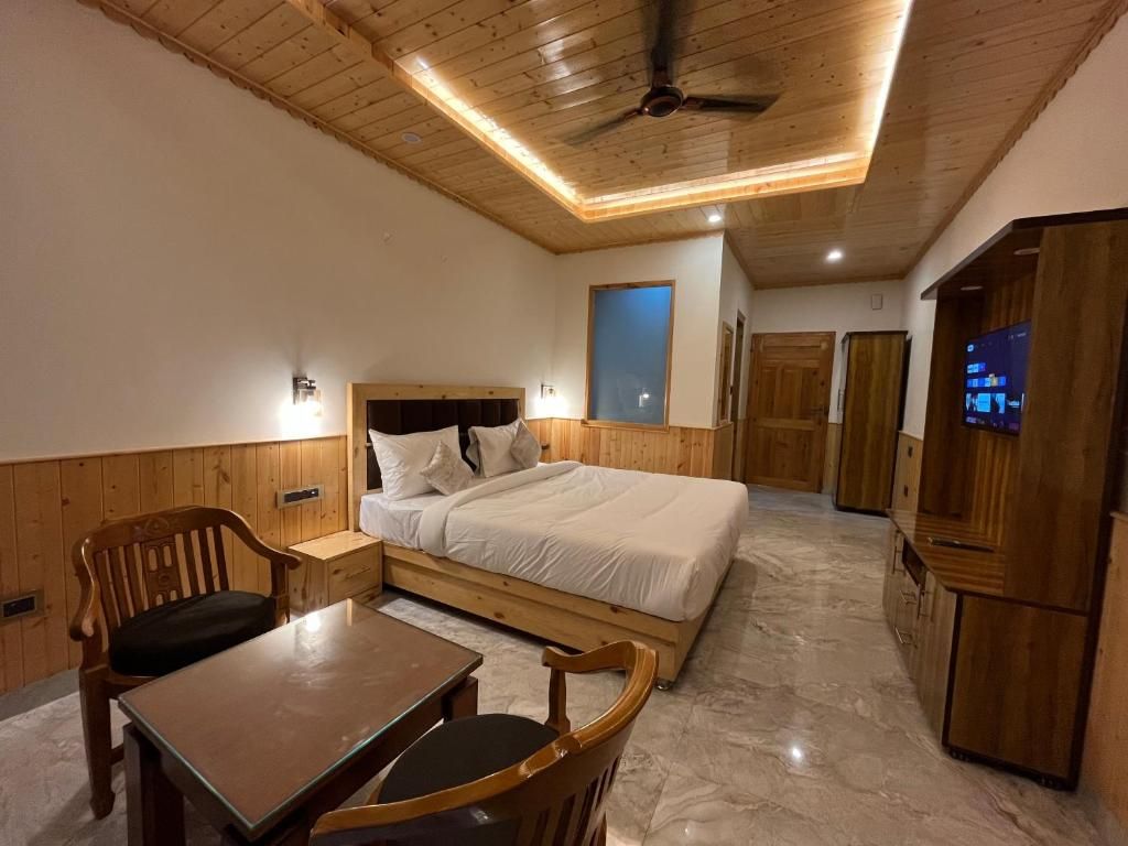 A bedroom with a bed, wooden furniture, a ceiling fan, and a television.