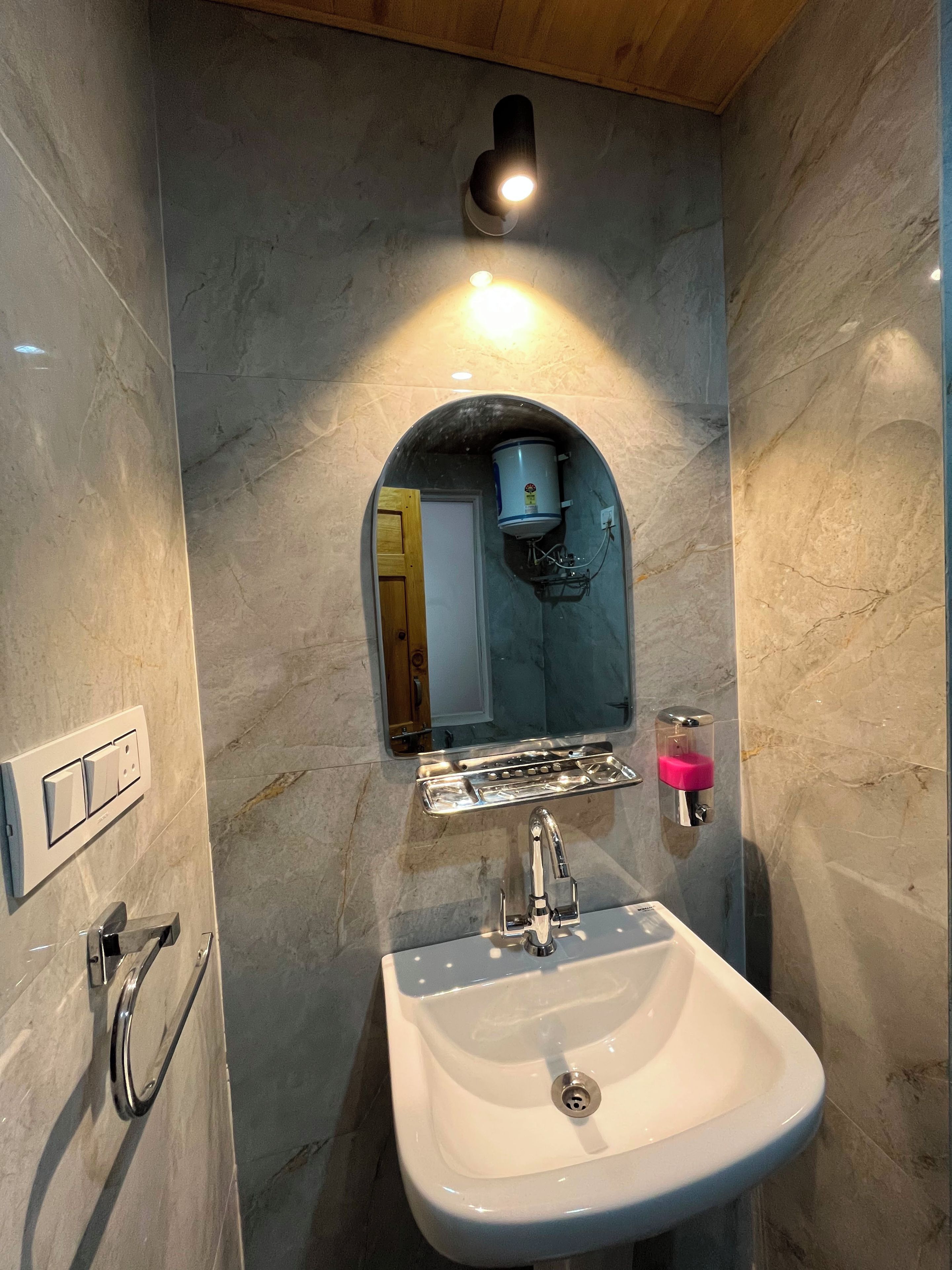Une salle de bain avec un lavabo blanc, un miroir, un porte-serviettes et une pomme de douche.