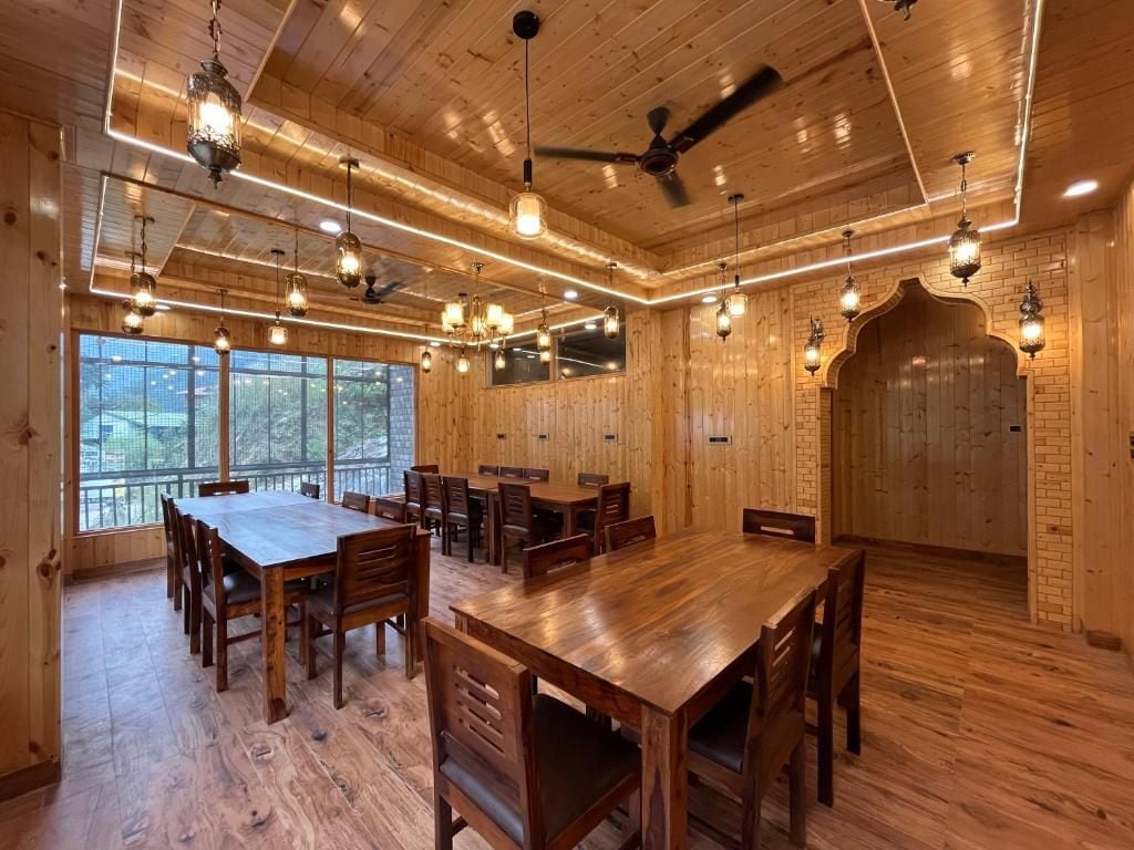 A spacious dining area with wooden tables and chairs, a ceiling fan, and pendant lighting.