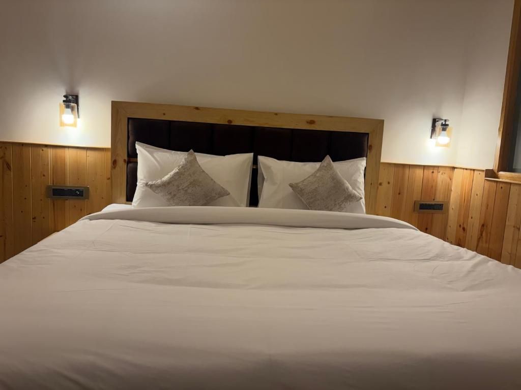 A bed with a wooden headboard, two wall-mounted lights, and a wooden panel wall.