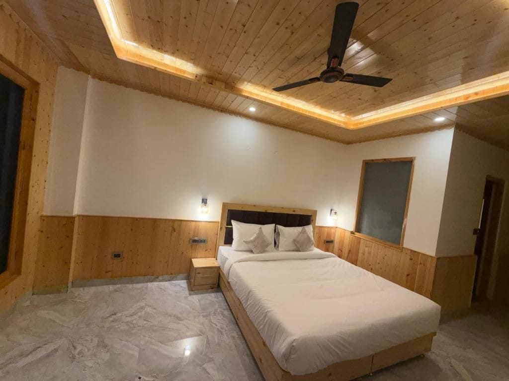 A bedroom with a wooden ceiling, a bed with white bedding, and a ceiling fan.