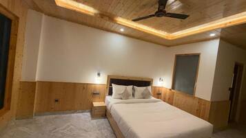 A bedroom with a wooden ceiling, a bed with white bedding, and a ceiling fan.