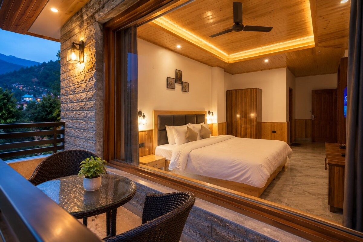 A hotel room with a bed, a nightstand, a mirror, a ceiling fan, and a balcony with wicker furniture.