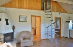 Una habitación amplia con chimenea, una escalera en espiral y una zona de cocina.