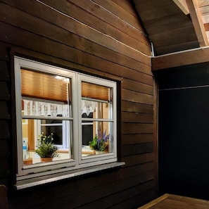 A window with a white frame, two potted plants, and a view of indoor furnishings. - Charming Hillside Cottage with Sauna (Wojcieszyce)