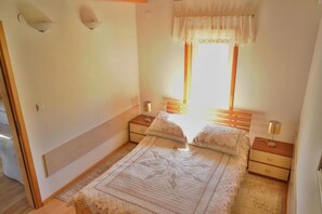 A bedroom with a bed, bedside tables, a window with curtains, and wall-mounted lights. - Charming Hillside Cottage with Sauna (Wojcieszyce)