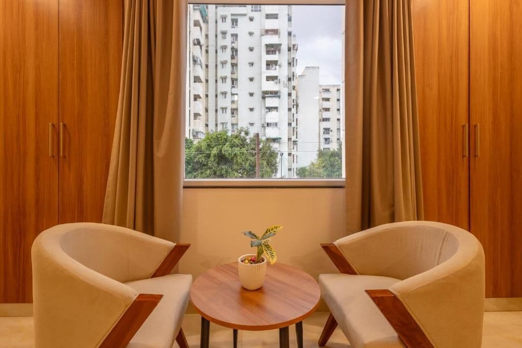 Una habitación con dos sillas, una mesita y una ventana con cortinas.