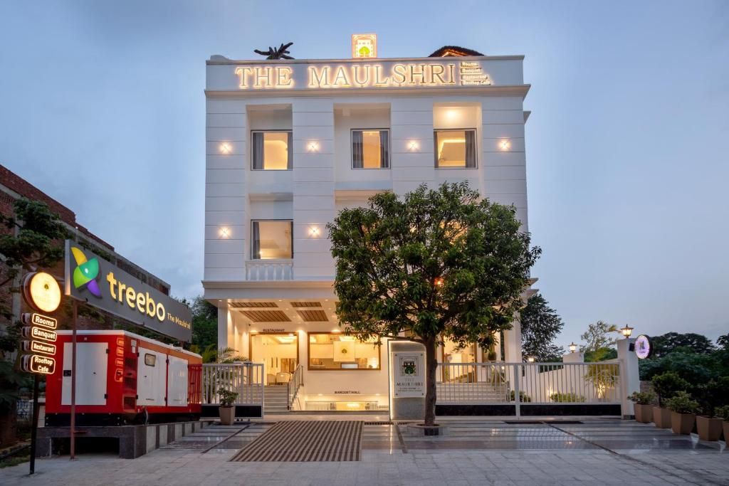 Et hotel kaldet 'The Maulshri' med et skilt, et træ foran og en bygning med flere etager.