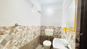 Ein Badezimmer mit Toilette, Waschbecken und Dusche. Die Wände sind mit einem geometrischen Muster geflieselt.