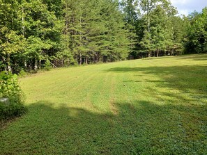 A grassy field with a fence and trees in the background. - TWG - Tent Campsite (4) (Graysville)