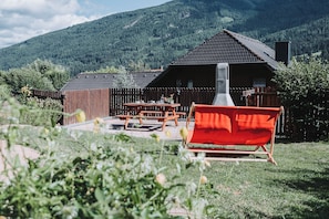 A wooden cabin with a tiled roof, surrounded by a wooden fence, and a red chair in the foreground. - Family-friendly apartment with a terrace and 1 bedroom (65 m2) (Sankt Michael im Lungau)