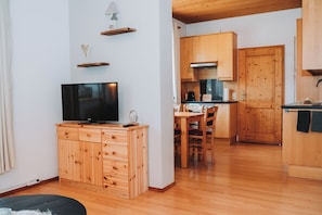 A compact living space with a TV on a wooden cabinet, a dining area with a table and chairs, and a kitchen with wooden cabinets and a stove. - Family-friendly apartment with a terrace and 1 bedroom (65 m2) (Sankt Michael im Lungau)