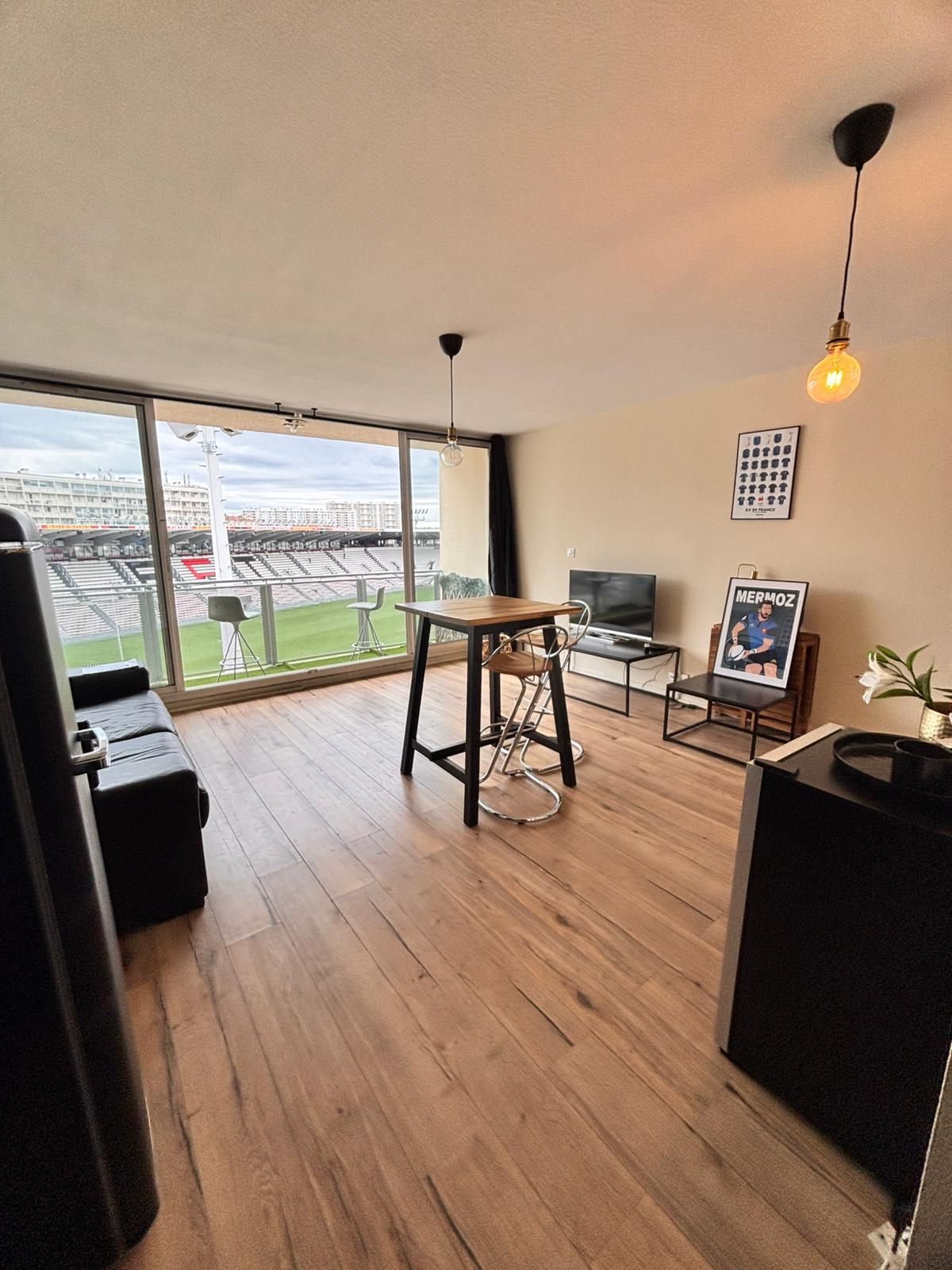 A modern living room with a large window, a dining area, and a TV.