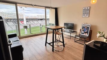 A modern living room with a large window, a dining area, and a TV.